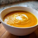 Bowl of creamy Buttercup Squash Soup swirled with cream, a comforting and delicious recipe.