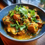 Close-up of Chicken Curry With Coconut Milk in a blue bowl, garnished with fresh cilantro.