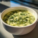 Close-up of a bowl of creamy Dill Pickle Soup, garnished with fresh dill.