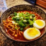 A bowl of Spicy Ramen with noodles, broth, egg, and green onions.