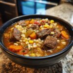 Close-up of a bowl of Vegetable Beef Barley Soup with beef chunks, barley, and vegetables.