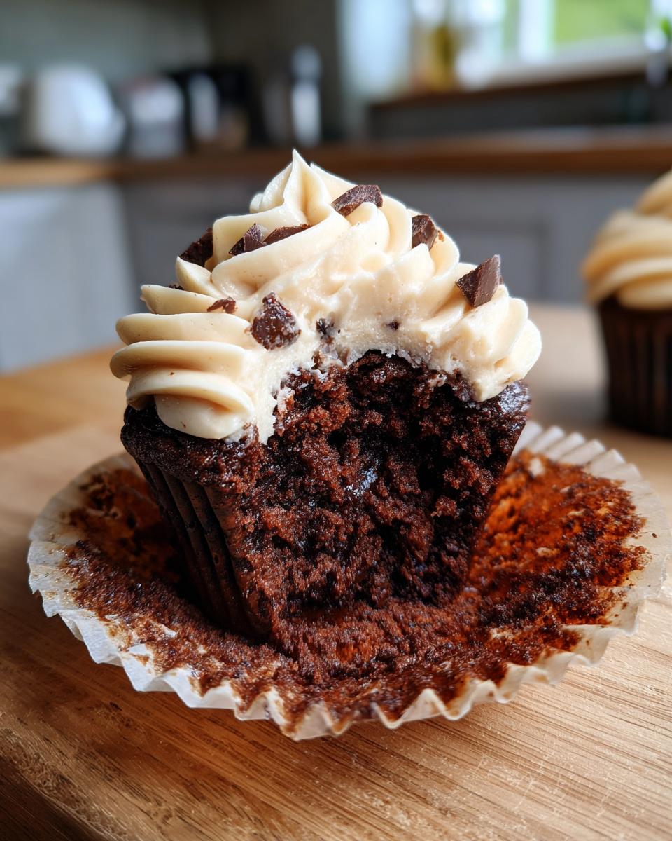 Close-up of a Chocolate Guinness Cupcake with frosting and chocolate chunks, showing the moist interior.