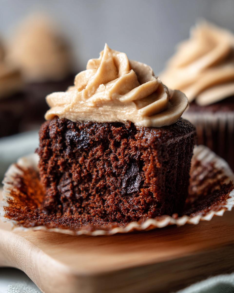 Close-up of a Chocolate Guinness Cupcake slice with frosting on a wooden board.
