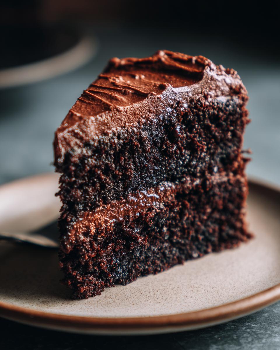 Close-up of a slice of Guinness Chocolate Layer Cake on a plate, showing the moist layers and frosting.