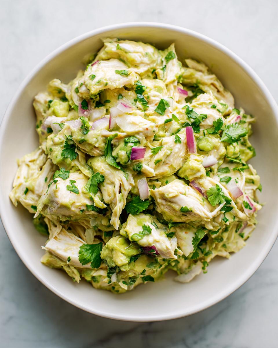 Overhead shot of a bowl filled with fresh Avocado Chicken Salad, with red onion and cilantro.