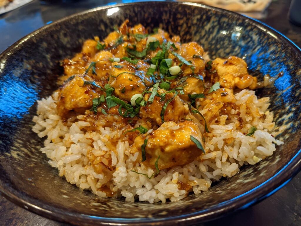 Close-up of a Buffalo Chicken Rice Bowl with chicken, rice, and fresh herbs.
