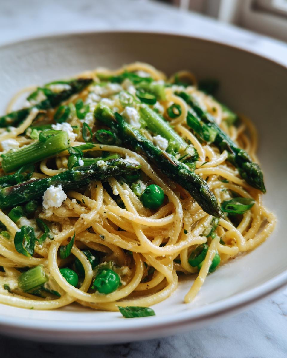 Close-up of Goat Cheese Pasta with Spring Vegetables, including asparagus and peas.
