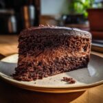 A slice of rich and moist Decadent Double Chocolate Cake on a plate, close-up.