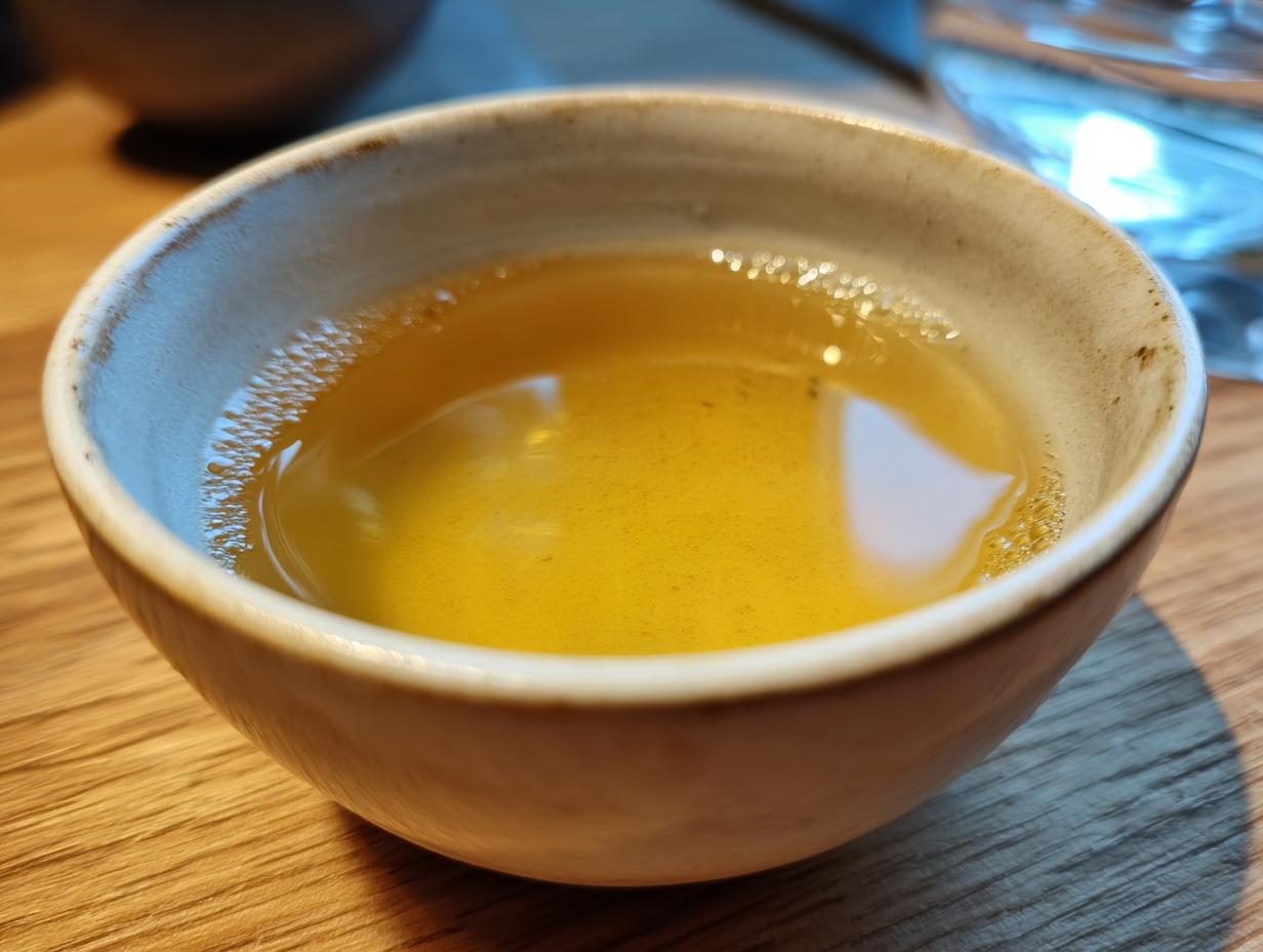 Close-up of a bowl of homemade fish broth for cats, golden color.