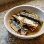 Close-up of fresh sardines in a white bowl, ready for a Fresh Sardine Cat Dinner.