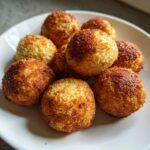 Close-up of a plate of homemade Grain-Free Fish Cat Treats, golden brown and spherical.