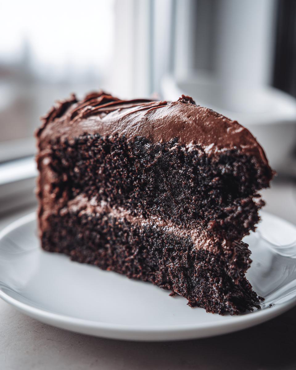 Close-up of a slice of Guinness Chocolate Cake with Irish Buttercream on a white plate.