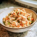 Close-up of a bowl filled with High-Protein Turkey Cat Food, with shredded turkey, peas, and carrots.