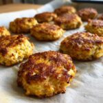 Close-up of freshly baked Homemade Salmon Cat Biscuits on parchment paper.