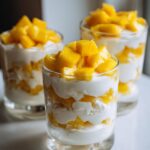 Three glasses of Mango Coconut Pudding Parfait layered with mango and coconut.