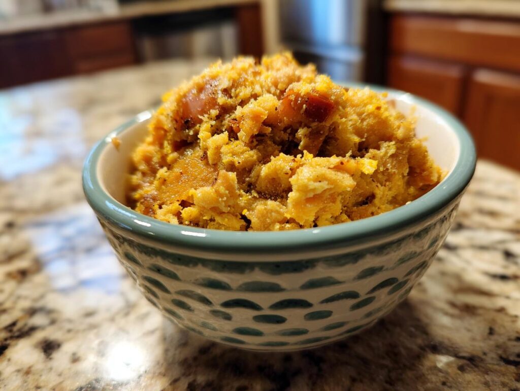 Close-up of a bowl filled with a homemade Raw Protein Cat Meal. The food is orange and textured.