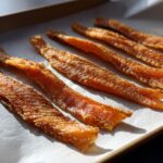 Close-up of crispy Salmon Skin Cat Treats on parchment paper, perfect for a healthy snack.