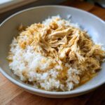 A bowl of homemade sensitive stomach cat meal, featuring rice and shredded chicken.