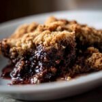 Close-up of a slice of Southern Chocolate Cobbler on a white plate, showing the rich chocolate filling and crust.
