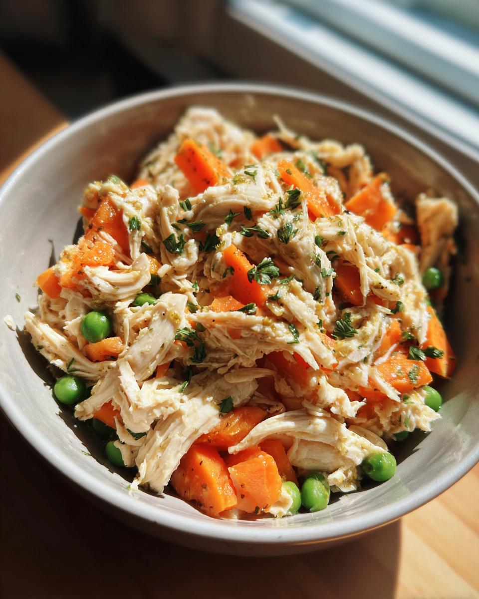 Close-up of a Spring Chicken Cat Meal Bowl with shredded chicken, carrots, and peas.