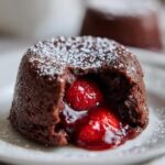 Close-up of a Strawberry Chocolate Lava Cake with a flowing strawberry center, dusted with powdered sugar.