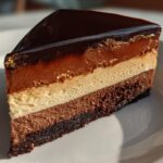 A slice of Triple Chocolate Mousse Cake with Silky Mirror Glaze, showing layers of chocolate mousse and a shiny glaze.