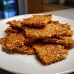 A stack of homemade Tuna & Oat Cat Crunchies on a white plate, close-up.