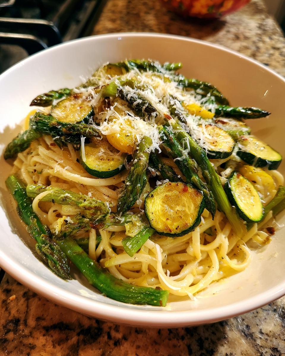 Close-up of a bowl of asparagus and zucchini pasta salad with parmesan cheese.