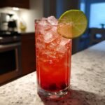 A vibrant Bay Breeze Cocktail in a tall glass, garnished with a lime slice and filled with ice.