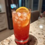 A vibrant Beach Cocktail recipe with ice and an orange slice, perfect for summer.