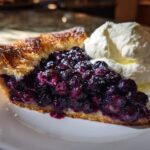 A slice of delicious Blueberry Galette with Vanilla Cream served on a white plate.