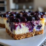 Close-up of a slice of Blueberry Lemon Cheesecake Bars topped with fresh blueberries.