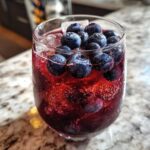 Close-up of a Blueberry Lemonade Vodka Smash cocktail with fresh blueberries and ice.