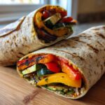 Close-up of two halves of Grilled Veggie & Hummus Wraps, filled with grilled vegetables.