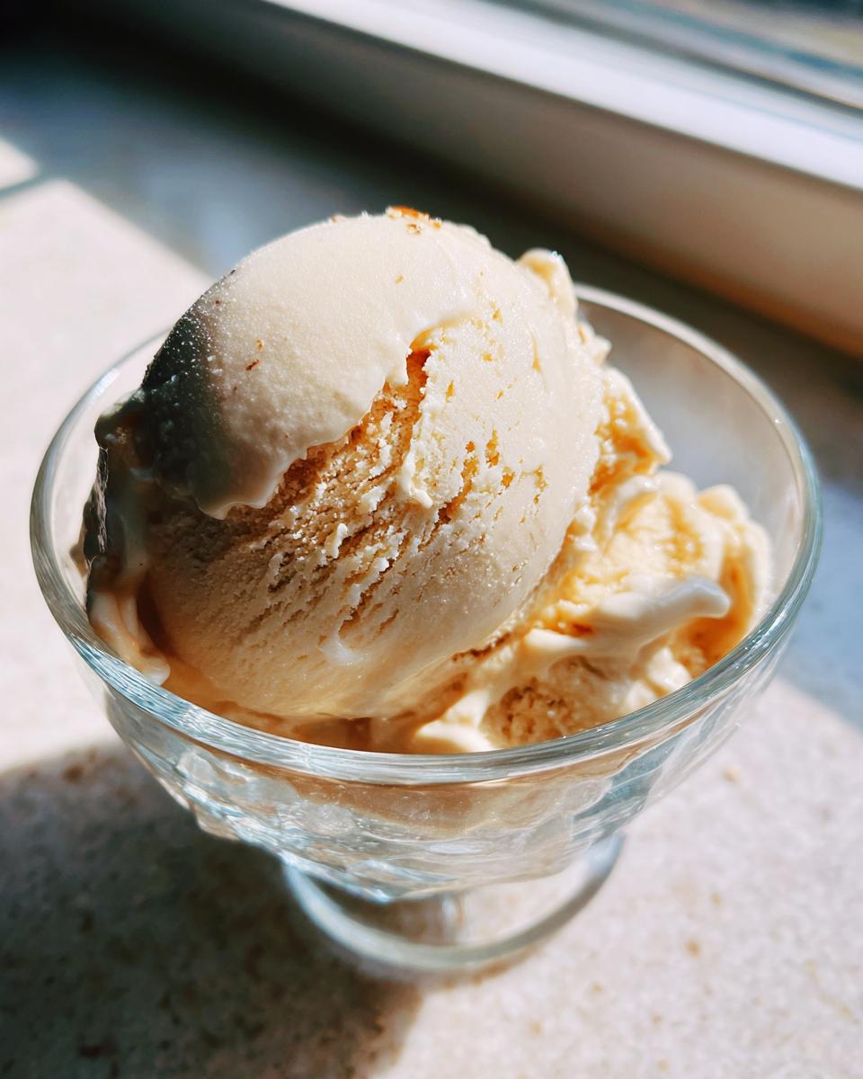 Close-up of a scoop of Honey Lavender Ice Cream in a glass dessert bowl, creamy and delicious.