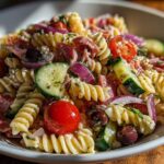 Close-up of a vibrant Italian pasta salad with rotini, tomatoes, olives, and zucchini. Pasta salad recipes italian easy.