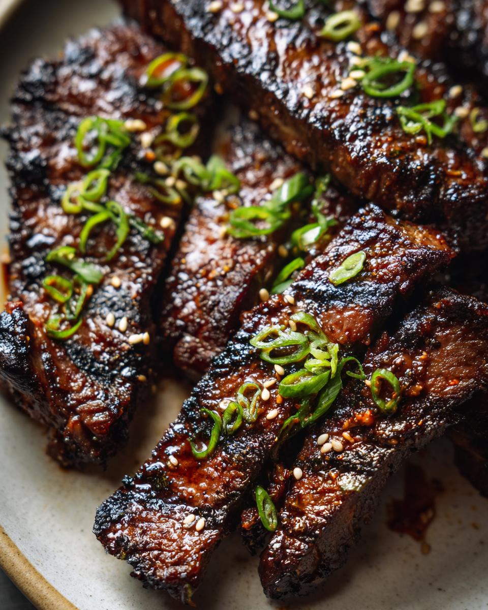 Close-up of Korean BBQ Beef Short Ribs, garnished with sesame seeds and green onions.