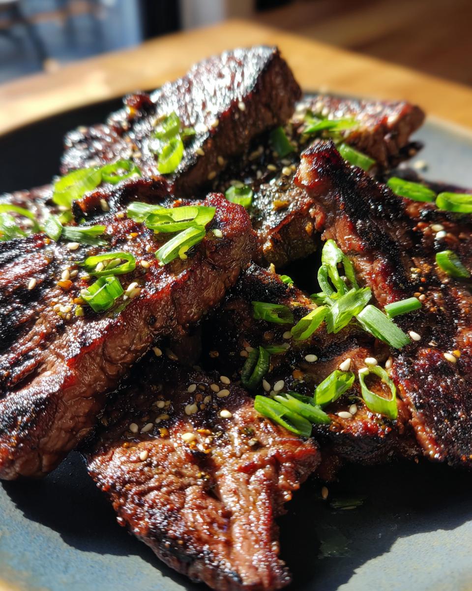 Close-up of grilled Korean BBQ Beef Short Ribs, garnished with sesame seeds and green onions.