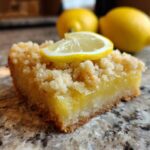 Close-up of a slice of Lemon Crumb Bars, topped with a lemon slice, perfect for dessert.