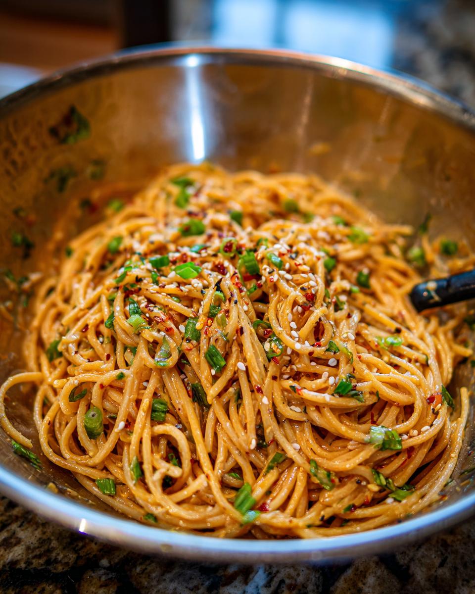 Close-up of a bowl of pasta salad asian with sesame seeds and green onions.