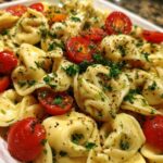 Close-up of pasta salad using cheese tortellini with tomatoes and herbs.