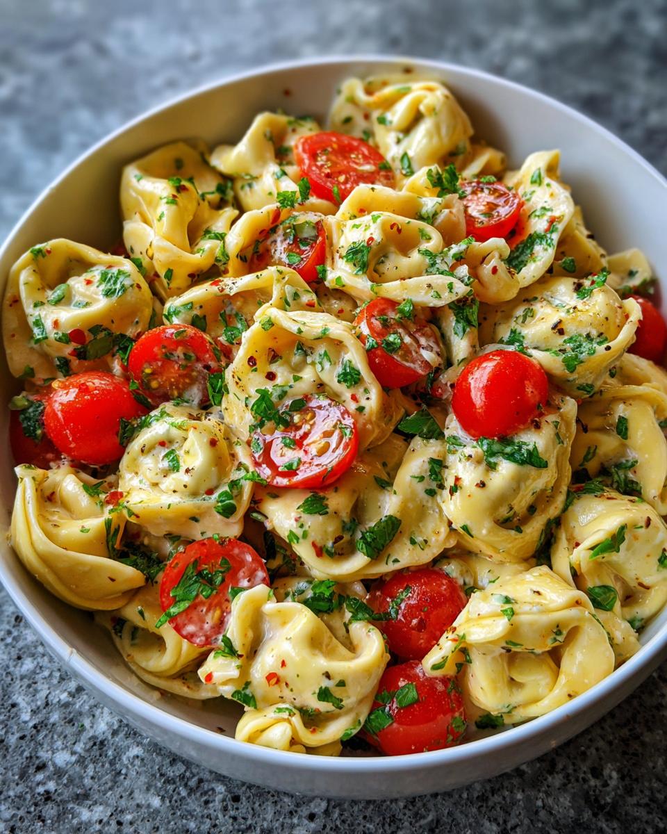 Close-up of a pasta salad using cheese tortellini with cherry tomatoes and herbs.
