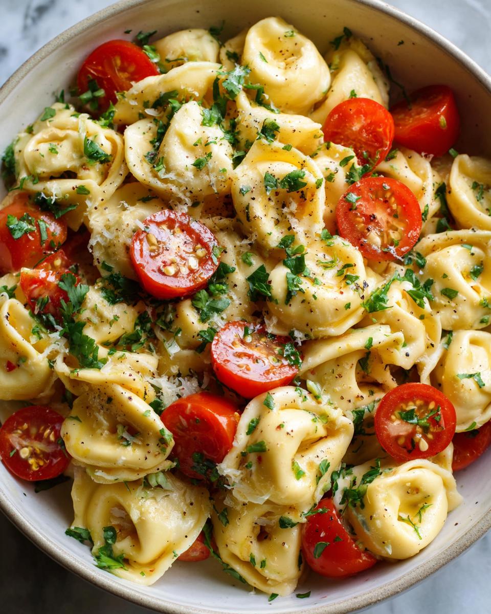 Close-up of pasta salad using cheese tortellini with cherry tomatoes and herbs.