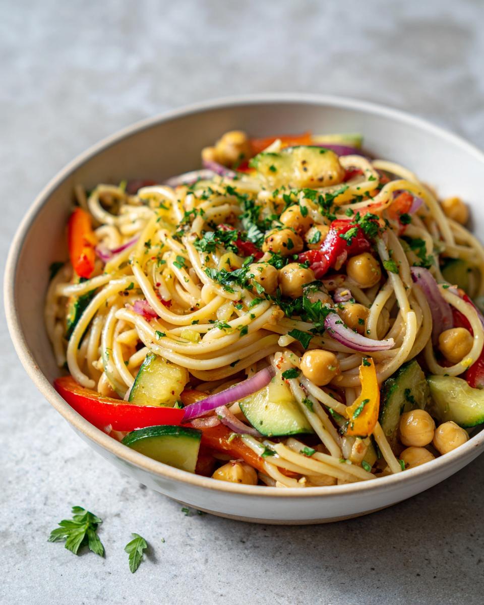Close-up of a bowl of pasta salad chickpeas with vegetables and herbs, ready to serve.
