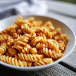 Close-up of pasta salad chickpeas in a white bowl, showing fusilli pasta and chickpeas.