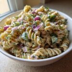 Close-up of a bowl of pasta salad cucumber with red onion and dill.