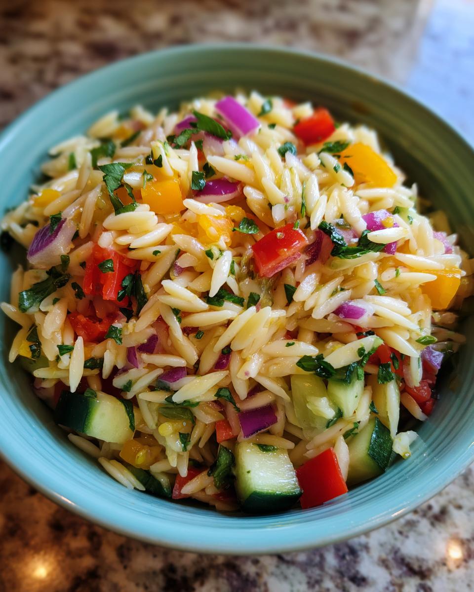 A vibrant bowl of pasta salad orzo with colorful vegetables and herbs.
