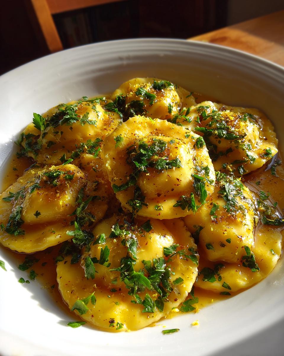 Close-up of Ricotta & Lemon Ravioli with brown butter sauce and fresh herbs.