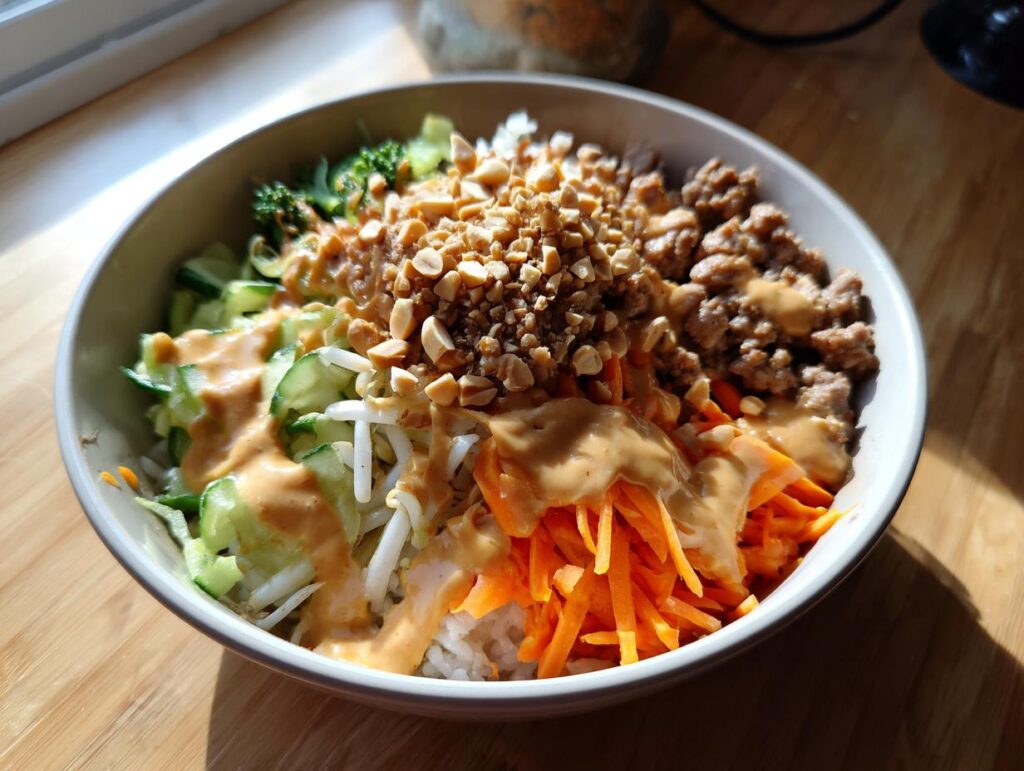 A colorful Spring Roll Bowl with Peanut Sauce, vegetables, and peanuts.