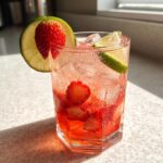 A vibrant Strawberry Lime Vodka Smash cocktail with fresh strawberries and lime slices.